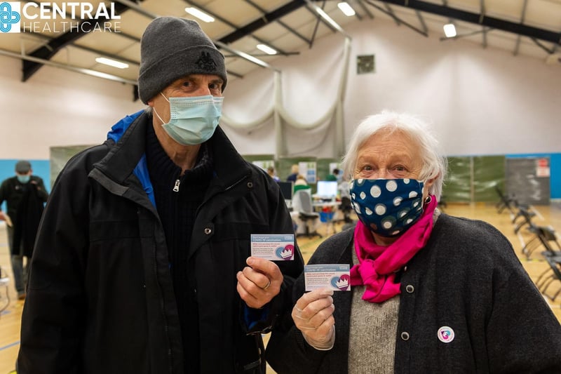 Valerie and John Nicholson hold up their vaccine cards.