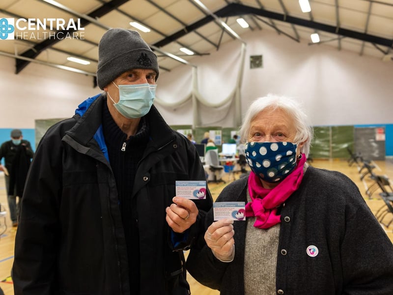 Valerie and John Nicholson hold up their vaccine cards.