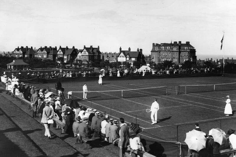 circa 1913: People watching a game of mixed doubles at the tennis courts at Scarborough.