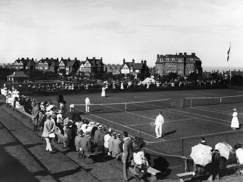 circa 1913: People watching a game of mixed doubles at the tennis courts at Scarborough.
