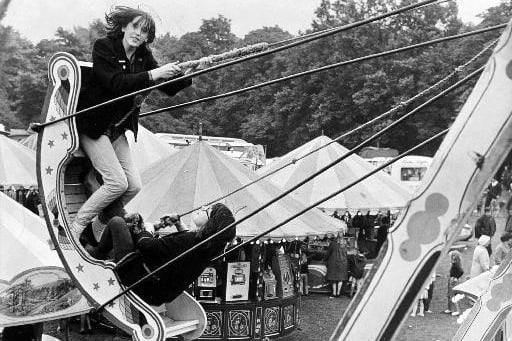 Two holidaymakers swing over the heads of the crowds at a fair held in Clarence Park in 1965.