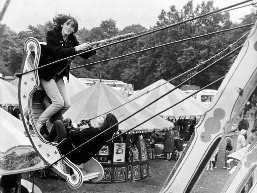Two holidaymakers swing over the heads of the crowds at a fair held in Clarence Park in 1965.