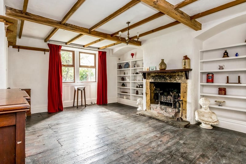 The spacious living room is bursting with character features including high ceilings, exposed beams, picture rails, stained glass features in the internal doors, open fireplace and built in shelving in the chimney alcove.