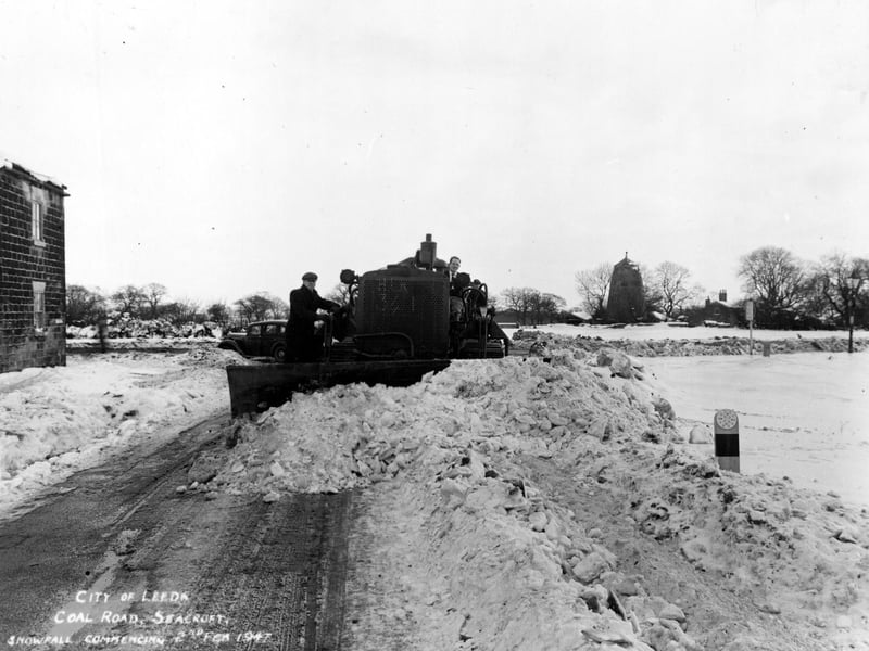 A snow plough at work on Coal Road. The old windmill on Mill Green can be seen in the background.