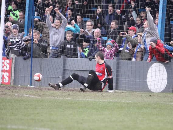 Halifax Town fans cheer as Buxton keeper Scott Hartley is sent the wrong way from the penalty spot.
