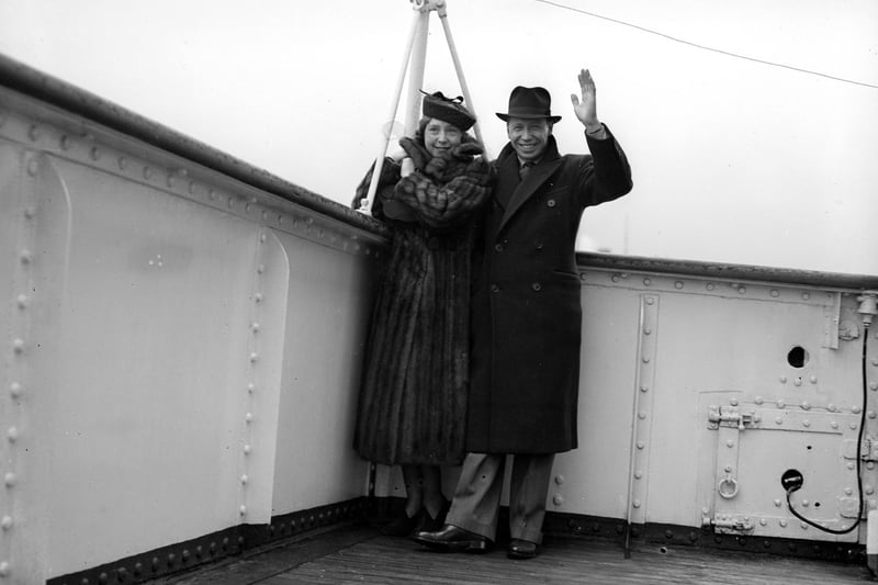 English entertainer George Formby give a jolly wave, pictured with his wife Beryl on board a ship in 1932.