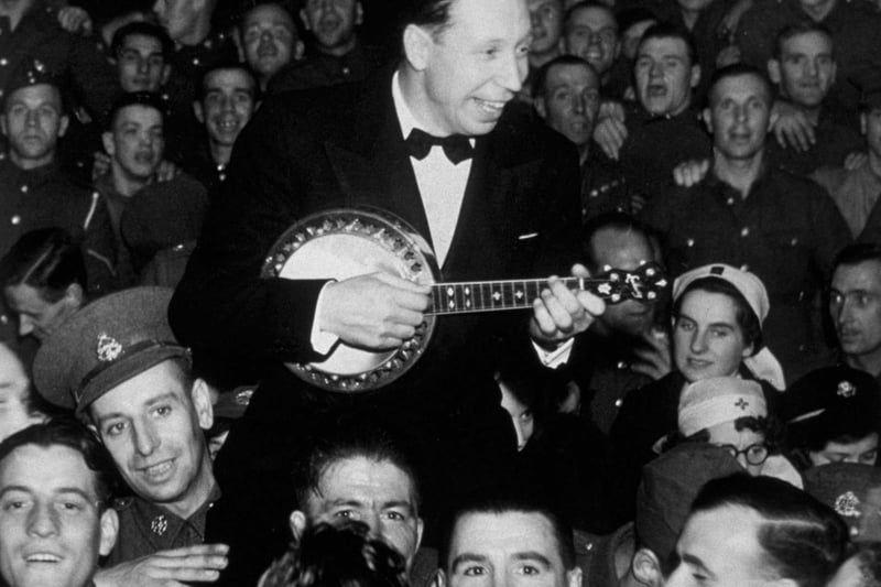 Actor and singer George Formby entertaining troops, playing in the crowd at a seaside concert hall in northern England in 1939