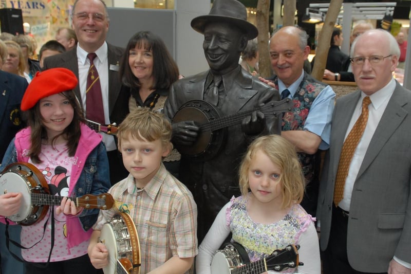 Wigan George Formby Society members with the newly sited statue of George in the Grand Arcade, from left, President and Secretary Gerry and Vivien Mawdsley, Neil Forshaw vice pesident, and member Dennis Mitchell, with youngsters, front from left, Francessca Davies, Charlie and Lizzie Jones.