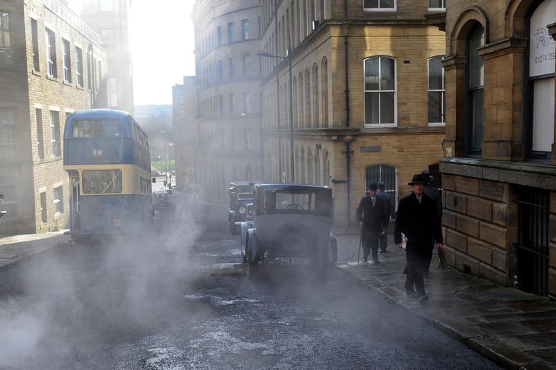 Extras were dressed in their own period attire as they strolled down a smoky street.