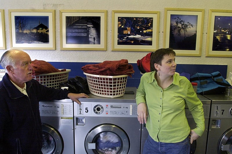 October 2001 and photographer Claire Harbottle shows Harehills resident Ron Leadbetter her images displayed on the walls of a local launderette.