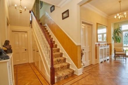 An incredibly spacious and inviting entrance hall with solid wooden flooring, under stairs storage cupboard, cloaks cupboard, dado rail, two radiators with ornate wooden covers, stairs leading to the first-floor accommodation.