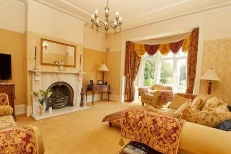Feature gas fireplace with a marble surround, double glazed bay window, radiator with an ornate wooden cover, picture rail, detailed ceiling.