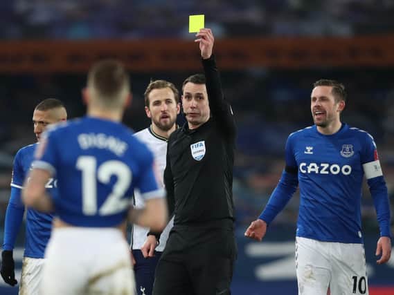 Everton's French defender Lucas Digne (front) is shown the yellow card by referee David Coote during the English FA Cup fifth round football match between Everton and Tottenham Hotspur at Goodison Park in Liverpool on February 10, 2021.