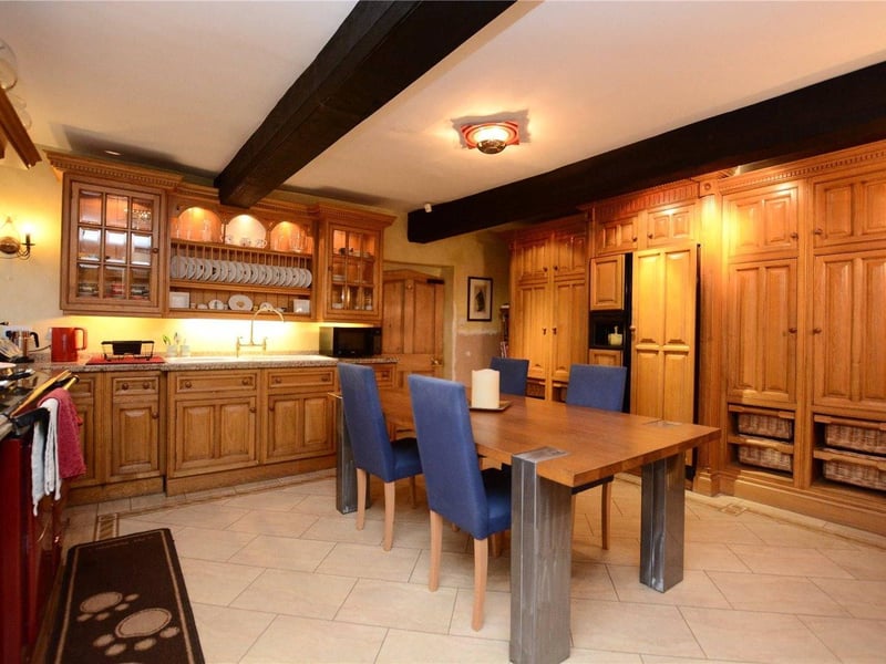Back upstairs, the kitchen sits in the oldest part of the house and boasts solid oak wall and base level units, with granite work surfaces, designed by Clive Christian. An integrated electric AGA, as well as a separate Britannia electric oven, dishwasher and double Belfast sink, sit on top of the luxury vinyl Amtico floor tiling. The kitchen leads through to a secondary beautifully wide entrance hall with feature curved walls and a foundation stone of 1667 depicting the original cottages construction date
