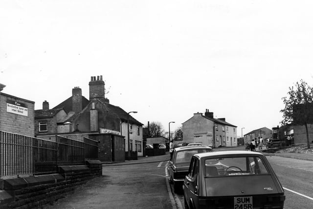 Church Street in Woodlesford by the junction with Highfield Lane. On the left is Woodlesford Junior and Infant School. Beyond the junction is a bus shelter; hidden behind this is Lotus Chop Suey Bar and Woodlesford Fisheries.