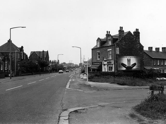 Bradford Road in June 1983 from the junction with Fenton Street. Next to this is a pair of shops, Millan Stores, off licence, then David Charles, hairdressers, who are having an extension built to the side.