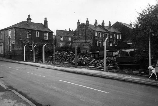 Albert Road in Morley showing a vacant site strewn with builders' rubble. Houses in the background face on to Ackroyd Street.