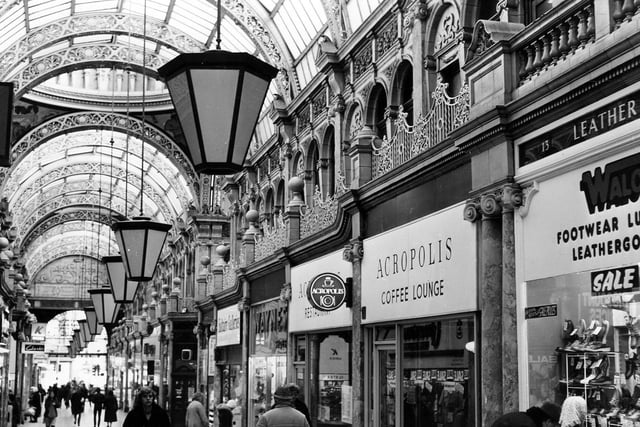 County Arcade looking in the direction of Vicar Lane. Shops include Saltaire Galleries, Waynes shoe shop, Acropolis Coffee Lounge and, at the right edge, Walco Footwear, Luggage and Leathergoods.