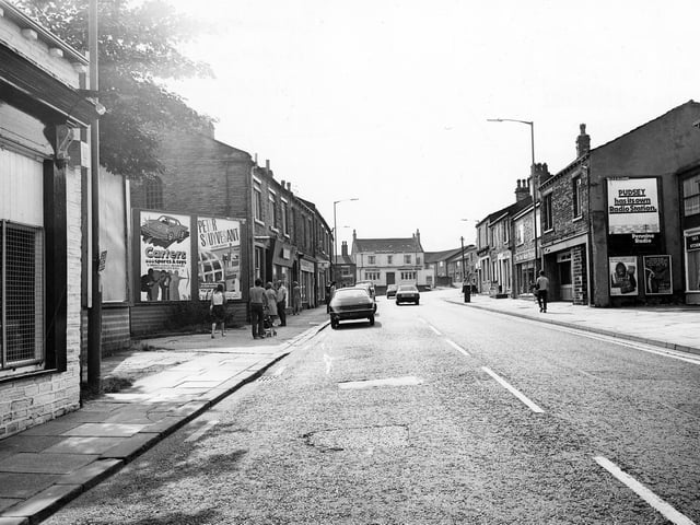Chapeltown looking towards the Commercial Hotel (centre) which stands at the junction with Uppermoor. There is a sign on a gable end (right) which reads 'Pudsey has it's own Radio Station, Pennine Radio'. Pictured in July 1982.