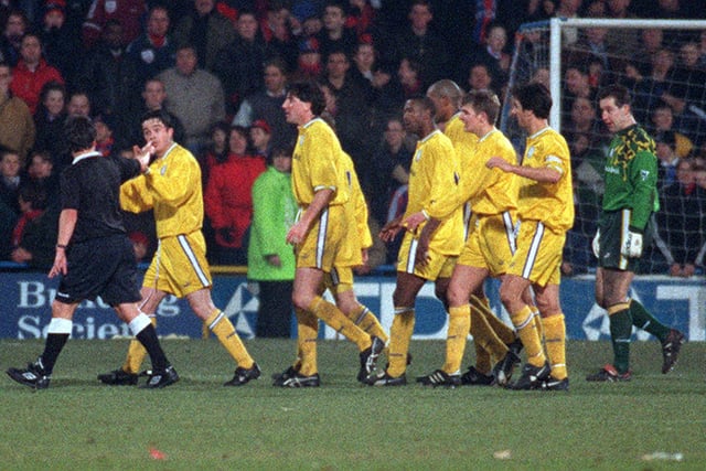 Leeds players protest to the referee Roger Dilkes over his decision to award Crystal Palace a penalty in the 88th minute.