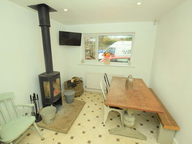 A stove is a feature within this space that could serve as dining area or snug.