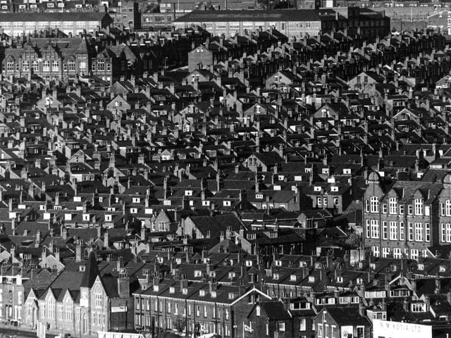 An aerial view over Chapeltown and Harehills from Roseville Road. Roseville Works is visible at the bottom edge. The camera looks across an area densely populated with red brick streets. On the right, the large brick building with decorative gables is the former Kepler Council School which was later known as Roseville County Secondary School.