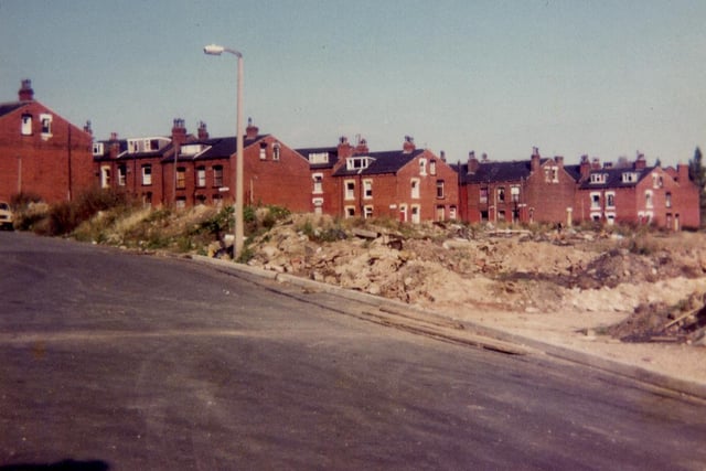 Armley Grove Place pictured in October 1983 showing in the foreground a cleared area where terraced housing has recently been demolished and in the background further rows of housing which are due to be demolished shortly. These are, from left, Fitzarthur Street, Fearnley Street, Gledhow Street and Simpson Street. Middle Cross Street runs across in front of them.