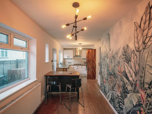 Towards the front of the property is the kitchen space, complete with additional breakfast bar and striking jungle-print feature wall.