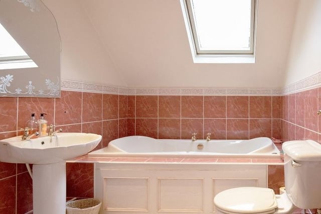 This luxurious tiled bathroom has natural light from a skylight window.
