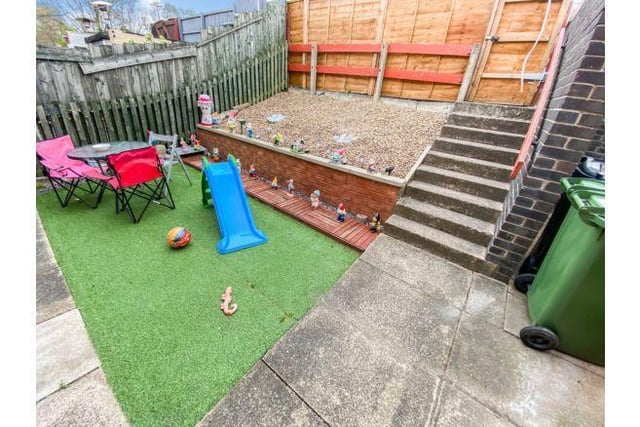 Outside there is an enclosed patio area and artificial grass.