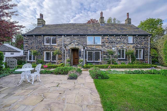 The stunning property with its stone front porch and wide patio area next to a lawn.