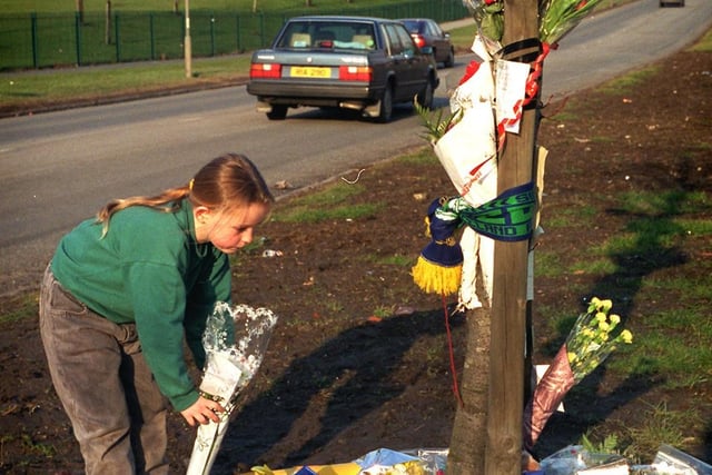 A school friend lays flowers at 'Wayne's tree' the spot where nine year old Wayne Rigby was killed as he crossed Oak Tree Drive in Gipton.