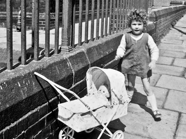 A little girl poses for the camera with her dolls' pram on Claremont Terrace in 1969. Whingate Primary School, which faces on to Whingate Road, dominates the background. This school opened as Whingate Council School in 1886 and remained here until 1989 when a new Whingate Primary School was built on the opposite side of Whingate Road. PIC: Eric Jaquier