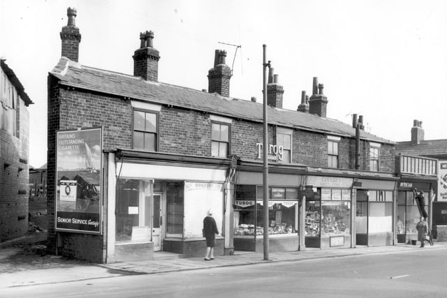 Armley Road in February 1964. Shops in focus include a bakers as well Mrs Hilda Cocker, a maker of darts and dartboards. The shop is called 'Variety Stores' and stocks electrical and household goods, cigarettes and also undertakes repairs to cigarette lighters. A fish and chip shop is next then an opticians. This was previously a branch of Thrift grocers.