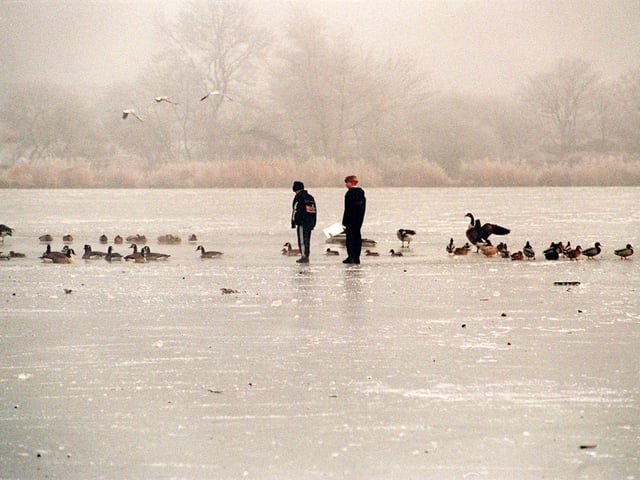 Two young boys walk across the frozen ice on Yeadon Tarn in December 1995.