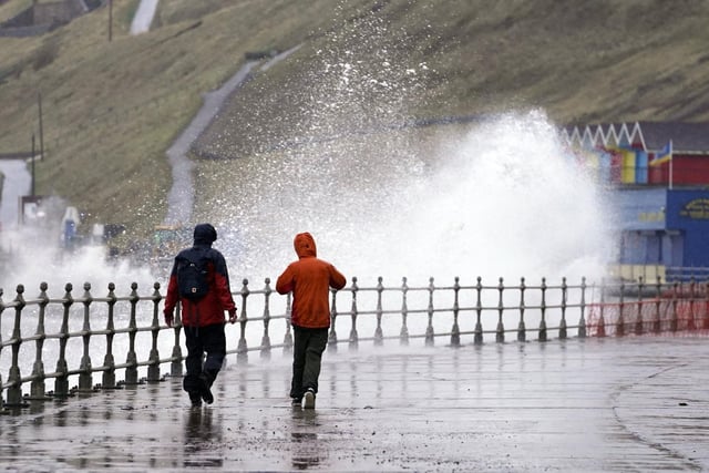 Whitby residents stroll along the coast as high waves threaten to overtop the seawalls. PA