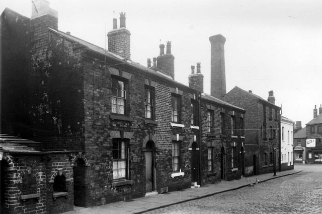 A view looks along the even numbered side of Grange Street in the direction of Wellington Road at Wortlkey in June 1959. On the left edge are the entrances to outside toilet blocks and middens.