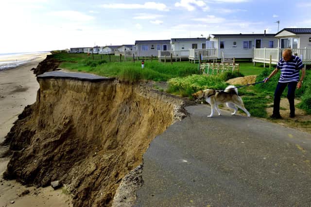 A dog walker comes perilously close to the edge on the former Ulrome to Skipsea road that most sections have fallen into the sea , due to the coastal erosion along the East Coast at Ulrome near Skipsea.
