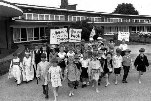 A press photograph of children celebrating Three Lane End School's 50th birthday with a pageant of 50 Years of Living History. Topics covered seem to include the coronation, rugby league, poverty and the miner's strike
