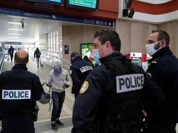 French policemen control the travel certificates of a passenger arriving at the Mulhouse main train station