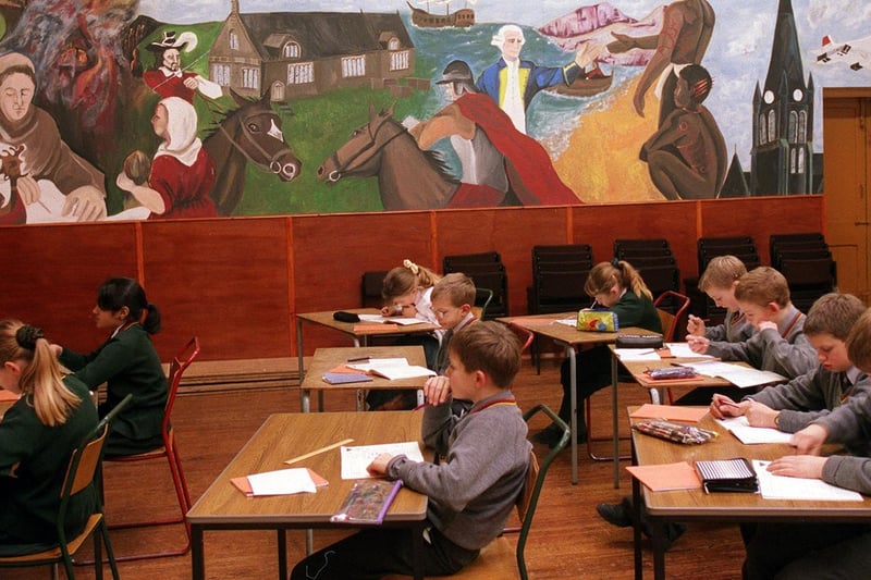 Children work in the shadow of a mural depicting the the 1,000 year history of Morley's St Mary in the Wood Church.