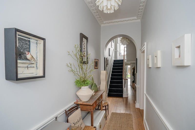 A grand entrance hall has a sweeping staircase leading to a half landing.