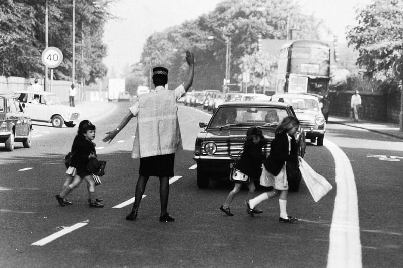 June 1975 and Beryl Davies helps school children cross Otley Road in Headingley.