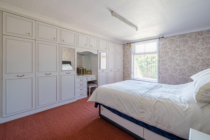 Fitted wardrobes and a dressing table are features of this room