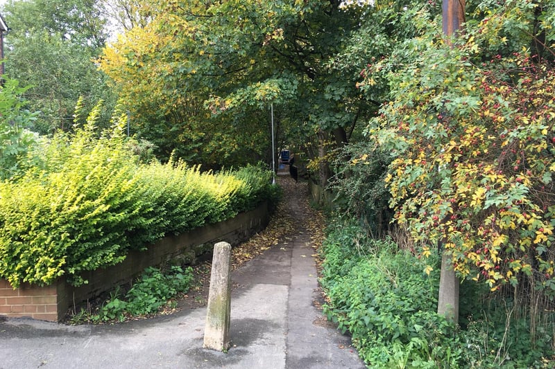 Come out onto Monk Bridge Road. Rather than crossing the road directly to Highbury Lane, for safety, turn right for fifty yards or so, to a pedestrian crossing. Return to the Lane, and at the far end of the Lane, directly ahead, enter the continuation of the old track through the Highbury ginnel (pictured). Follow the ginnel for 80 or so yards, with Meanwood Beck on the right at first, and then the tail race of the former mill. The Highbury ginnel and the old track arrive at Wood Mill, and end in a footpath T-junction. The path to the right leads into Tannery Park, on the site of Wood Mill.