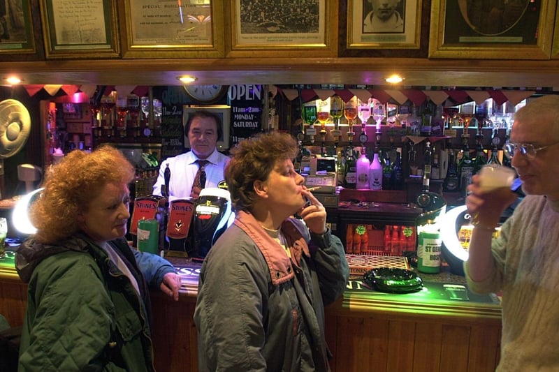 March 2004 and regulars enjoy a cigarette and a pint of beer at Delaney's Bar in Harehills,