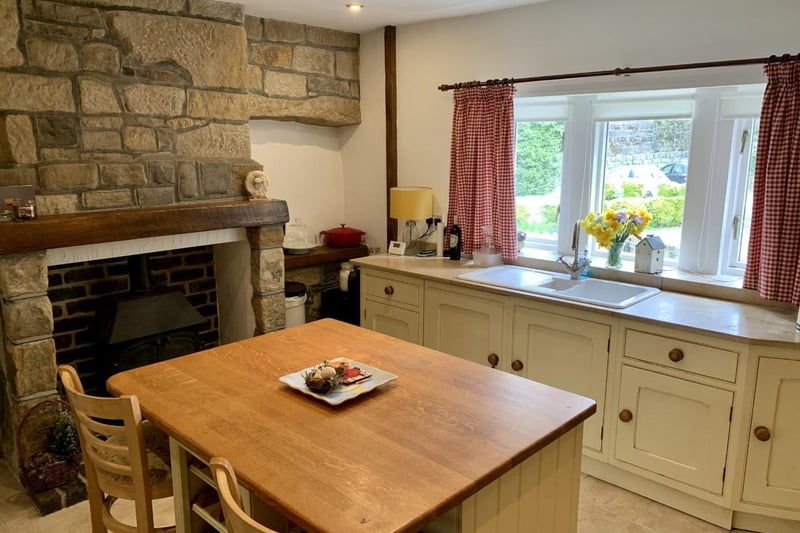 A stone wall and fireplace feature within the kitchen, that has lovely views from its window