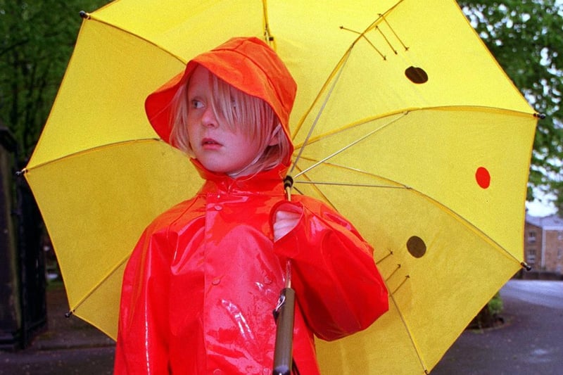 Amy Linnegan takes shelter from the rain whilst watching the parade at Ilkley Carnival in May 1997.