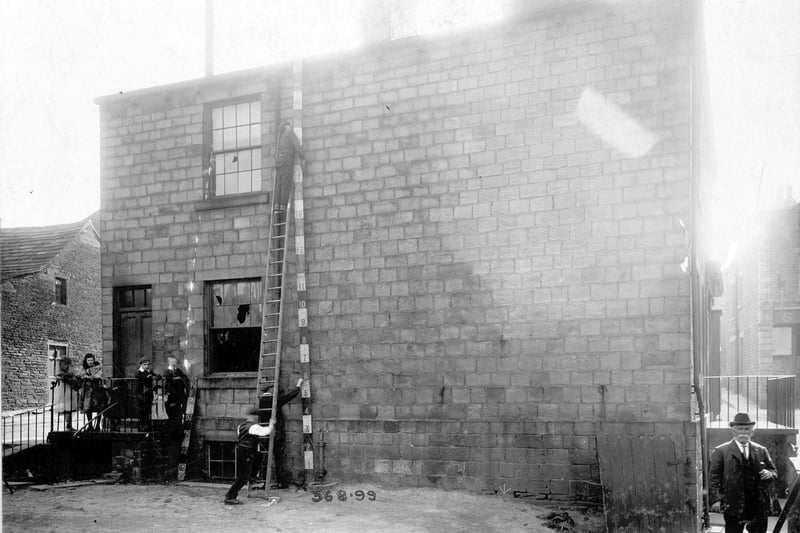 May 1909. The rear view of property which was to be demolished on Town Street. 
The site was used for a new Poor Rate Office. A small group of children on the left are watching workmen measuring the building.