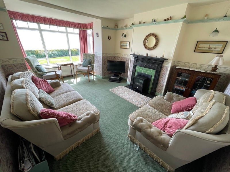 A lovely old fireplace and large picture window are features of the sitting room